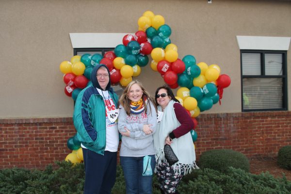 Three people standing in front of custom balloon sculpture