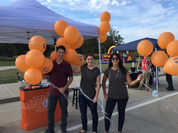 3 people holding onto bunches of custom balloons